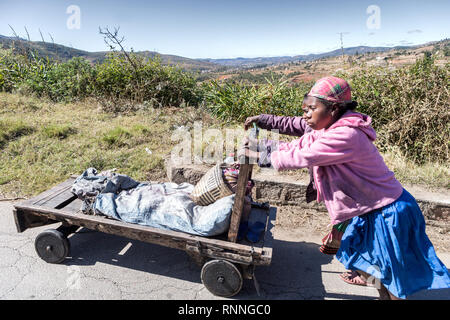 Vues sur la N7 route de Antsirtabe au Parc National de Ranomafana Madagascar -femmes poussant un chariot le long de la route Banque D'Images