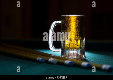 Congelés froid isolé beer mug avec billard cues sur fond noir Banque D'Images