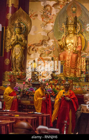 Les moines bouddhistes l'exécution d'un rituel dans Grande salle de prière, Buddha Tooth Relic Temple. Maitreya Bouddha en arrière-plan sur la droite, sur la gauche du Bodhisattva.