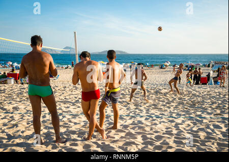 RIO DE JANEIRO - Janvier 2017 : un groupe de jeunes hommes jouent pied volley, un sport hybride de volley-ball et de soccer sans les mains ou les bras. Banque D'Images