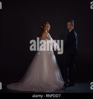 Mystérieux et romantique, la mariée et le marié. Câlins ensemble. L'homme et de la femme, robe de mariage. Tenez les mains des amoureux Banque D'Images