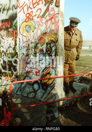 Un policier est-allemand ressemble à un petit sapin ornant le côté de l'Allemagne de l'ouest du mur de Berlin. La garde côtière est debout à la nouvelle ouverture dans le mur de Berlin à la Potsdamer Platz. Banque D'Images