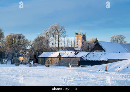 D'Avebury et cercle de St James Church dans la neige de l'hiver juste après le lever du soleil. Avebury, dans le Wiltshire, Angleterre Banque D'Images