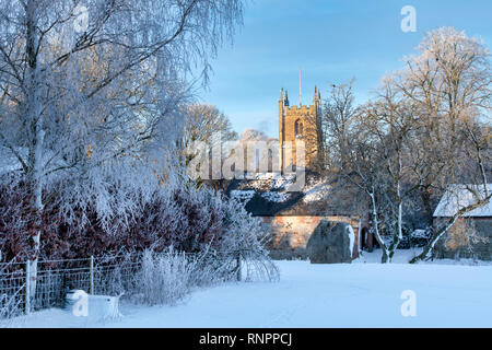 D'Avebury et cercle de St James Church dans la neige de l'hiver juste après le lever du soleil. Avebury, dans le Wiltshire, Angleterre Banque D'Images