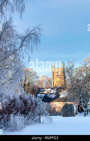 D'Avebury et cercle de St James Church dans la neige de l'hiver juste après le lever du soleil. Avebury, dans le Wiltshire, Angleterre Banque D'Images