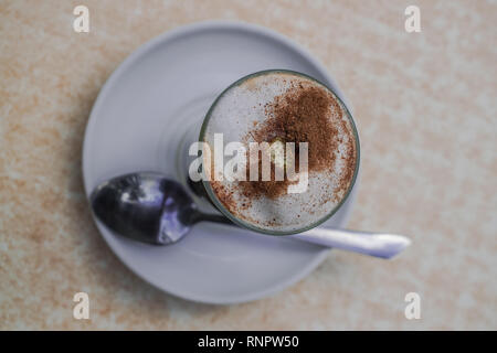 Café avec du lait et la cannelle, avec cuillère sur un plat blanc Banque D'Images