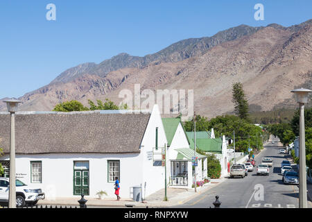 Church Street, Montagu, Western Cape, Afrique du Sud avec l'ancienne architecture coloniale et à la vue des montagnes Langeberg. Dame africaine dans les vêtements lumineux Banque D'Images