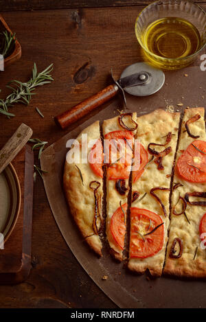 Vue de dessus de la focaccia en tranches avec oignons caramélisés Tomates et romarin frais Banque D'Images