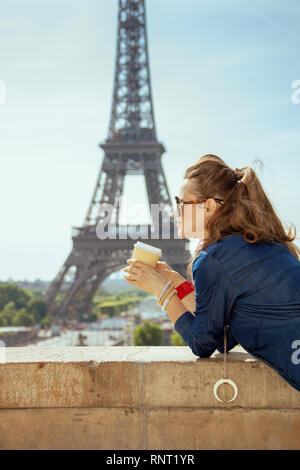 Voyageur branché la femme en bleu jeans dans l'ensemble de boire du café contre la tour Eiffel à Paris, France. Banque D'Images