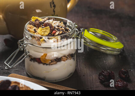 Photo horizontale de yaourt blanc. Le yaourt est en petit pot de verre avec métal serrure et couvercle hermétique. Muesli avec des aliments secs est stratifié dans et sur le yogourt. G Banque D'Images