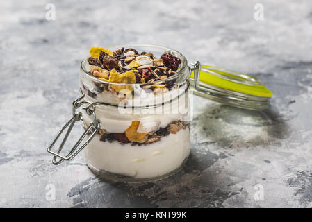 Photo horizontale de yaourt blanc. Le yaourt est en petit pot de verre avec métal serrure et couvercle hermétique. Muesli avec des aliments secs est stratifié dans et sur le yogourt. G Banque D'Images