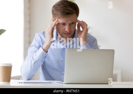 Tired businessman sitting at desk souffrant de maux de tête Banque D'Images