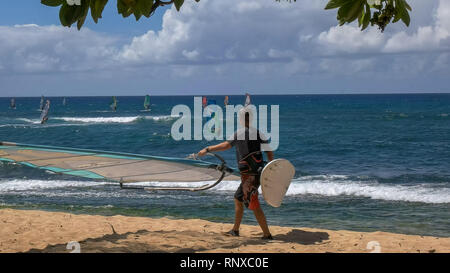 Para, États-Unis d'Amérique - le 10 août 2015 : marin porte leur conseil et la voile sur la plage de Ho'okipa Banque D'Images