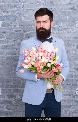 Inviter ses sorties. Homme romantique avec des fleurs. Cadeau romantique. Macho prêt date romantique. En attente de Darling. Tulipes pour ma chérie. Homme très soigné porter Bow-tie tuxedo tenir fleurs bouquet. Banque D'Images