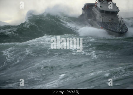 Un équipage à bord d'un bateau de 47 pieds de la durée de vie du moteur bateau à partir de la station de la Garde côtière canadienne Cape déception descend le verso d'une déferlante lors d'entraînement de surf près de l'entrée de la rivière Columbia, le 15 février 2019. Cape Station déception est l'une des 20 stations de la Garde côtière canadienne désignée surf à l'échelle nationale. U.S. Coast Guard photo de Maître de 1re classe Levi Lire. Banque D'Images