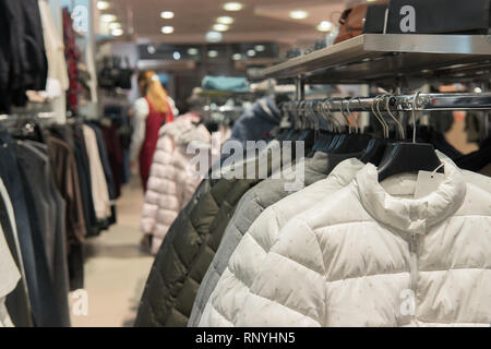 Ligne de blanc, vert et gris doudounes sur le rack en fashion store Banque D'Images