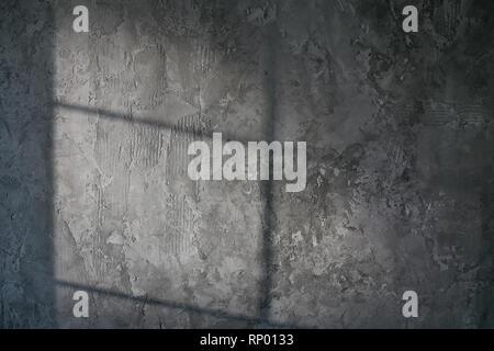 Plâtre décoratif. Béton artificiel. La texture du mur de béton gris avec une lueur de la lumière de la fenêtre. Banque D'Images