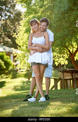 Smiling young couple standing in park Banque D'Images