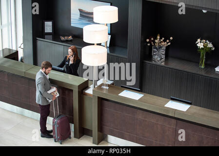 Réceptionniste femme de parler au téléphone tout en businessman standing at counter Banque D'Images