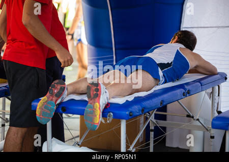 Étendu sur un lit de l'athlète tout en ayant les jambes massées après un entraînement physiques sportives. Banque D'Images