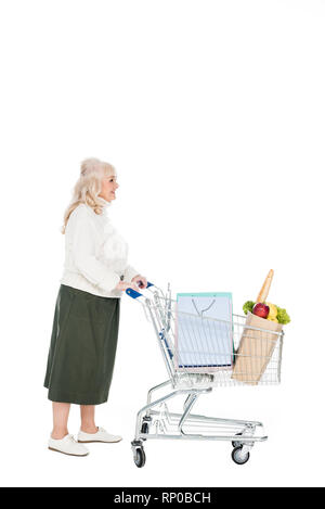 Cheerful retired woman walking avec panier à provisions et les sac de papier avec des provisions isolated on white Banque D'Images