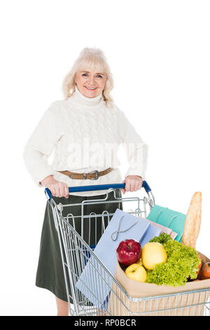 Smiling senior woman holding shopping bags avec panier et sac de papier avec des provisions isolated on white Banque D'Images