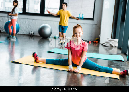 Kid excité faisant de la ficelle sur tapis de sol fitness jaune Banque D'Images