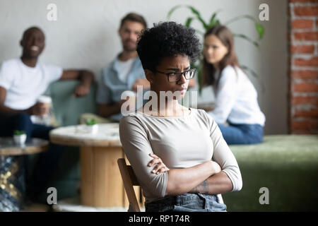 Black girl paria assis en dehors de leurs pairs dans une cafétéria Banque D'Images