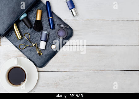 Sac à main femme de couleur bleu foncé et des cosmétiques avec tasse de café Banque D'Images