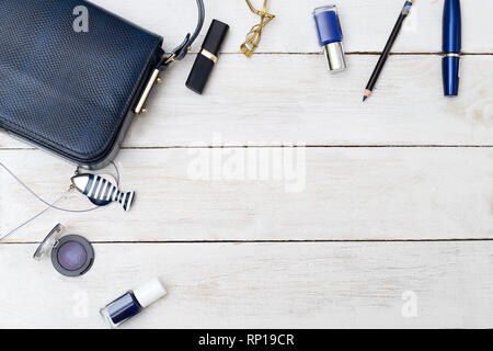 Sac à main femme de couleur bleu foncé et de cosmétiques sur un fond de bois. Copy space Banque D'Images