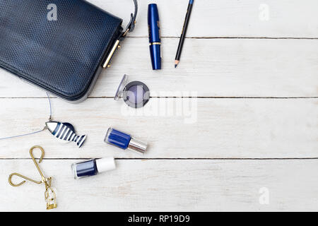 Sac à main femme de couleur bleu foncé et de cosmétiques sur un fond de bois Banque D'Images