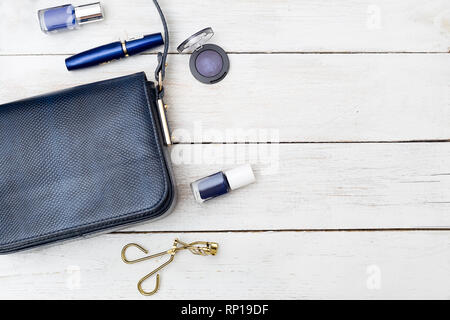 Petit sac à main femme de couleur bleu foncé et de cosmétiques sur un fond de bois Banque D'Images