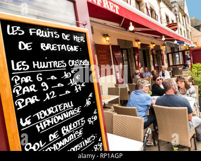 RESTAURANT DE FRUITS DE MER BRETAGNE CONCARNEAU BLACKBOARD ALFRESCO Les Fruits de Mer menu Tableau noir y compris les huîtres et crabe mayonnaise à l'extérieur en plein air avec restaurant typique français smiling diners à l'extérieur de Ville Close Concarneau Vieille Ville Bretagne Bretagne France Banque D'Images