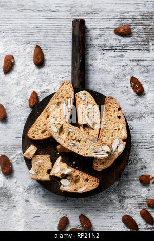 Portrait de quelques carquinyolis, pâtisseries typiques de la Catalogne, en Espagne, à base d'amandes, sur un plateau de bois rond, placé sur un livre blanc en bois rustique Banque D'Images