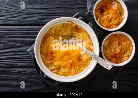 Gratin de pommes de terre cuite au four avec de la crème, des oignons et du fromage cheddar close-up dans une casserole sur la table. haut horizontale Vue de dessus Banque D'Images