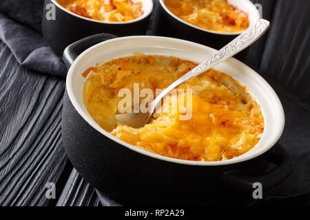 De pommes de terre maison en cocotte avec de la crème, des oignons et du fromage cheddar close-up dans une casserole sur la table horizontale. Banque D'Images