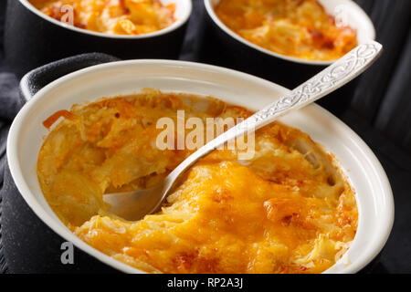 De pommes de terre savoureuse cocotte à la crème sure et le fromage cheddar close-up dans une casserole sur la table horizontale. Banque D'Images