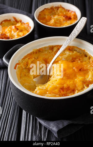 Cocotte Romanoff russe à base de pomme, la crème sure et le fromage cheddar close-up dans une casserole sur la table verticale. Banque D'Images