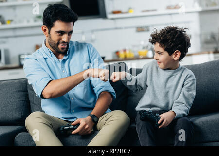 Cheerful Amérique père l'fist bump en fils après avoir joué au jeu vidéo à la maison Banque D'Images