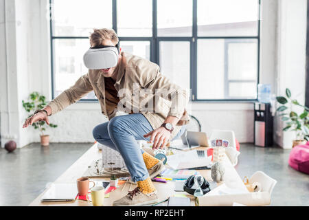 Designer hommes gesticulant avec les mains tout en ayant l'expérience de réalité virtuelle bureau loft Banque D'Images