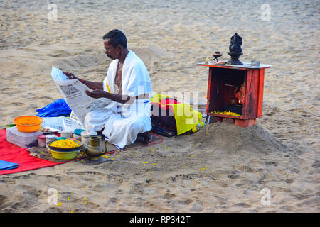 Prêtre hindou lecture journal avant rituel hindou sur Varkala Beach, Varkala, Kerala, Inde Banque D'Images