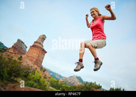 Happy young woman saute joyeusement dans l'air lors d'une randonnée. Banque D'Images