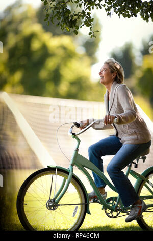 Smiling middle aged woman riding son vélo dans le parc. Banque D'Images