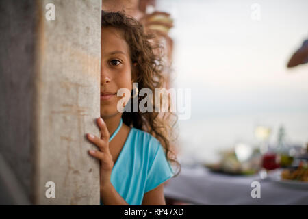 Portrait d'une jeune fille se cacher derrière un poteau. Banque D'Images