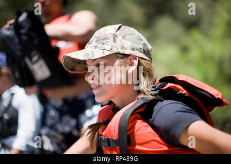 Young adult woman rowing le long d'une rivière. Banque D'Images