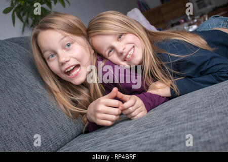 Les filles sont couchées sur le canapé, riant et s'amusant Banque D'Images