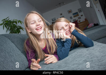Les filles sont couchées sur le canapé et de rire Banque D'Images