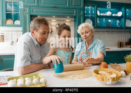 Girl making cookies avec les grands-parents Banque D'Images