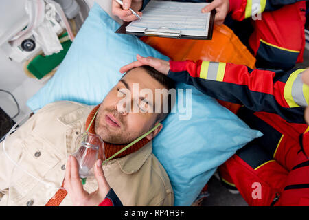 Portrait de paramedic putting on masque à oxygène sur patient inconscient Banque D'Images