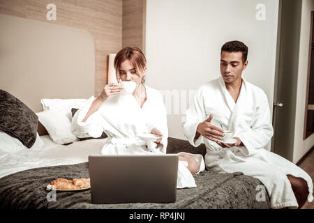 Couple de pigistes port hôtel peignoirs drinking coffee in bed Banque D'Images